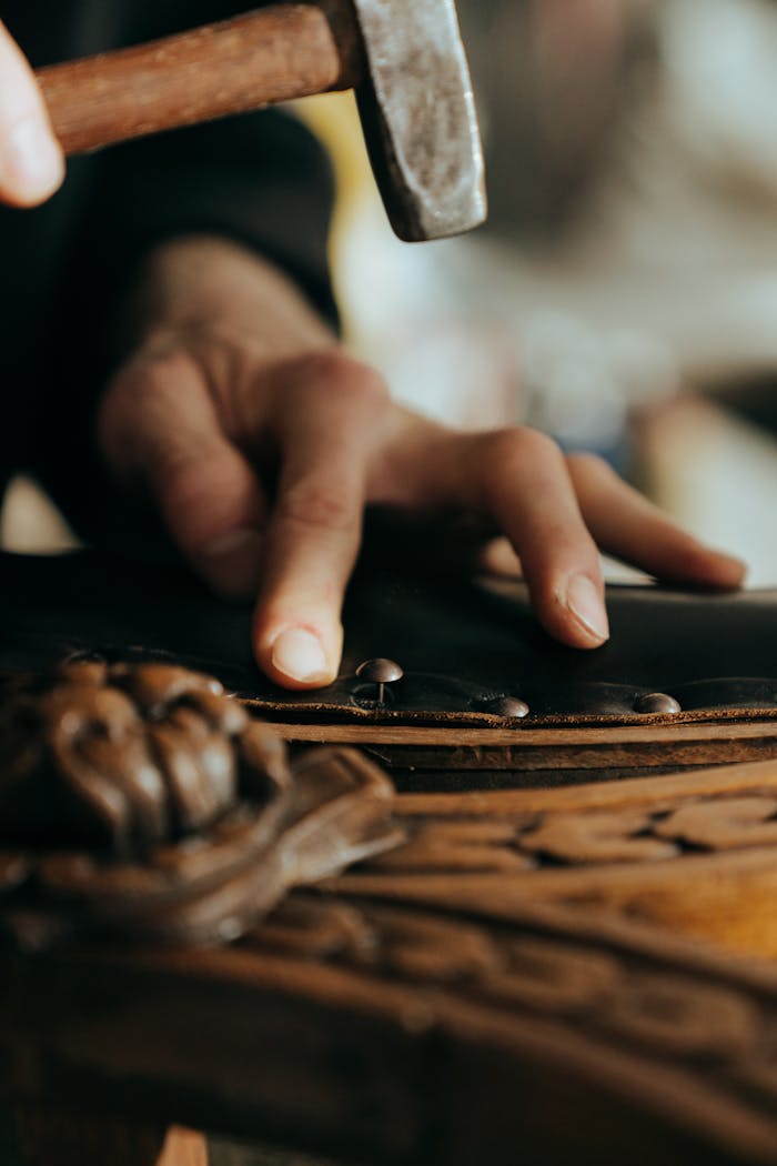 Close-up of a craftsman working on vintage wooden furniture in a workshop setting.